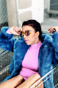 Woman wearing sunglasses while sitting in shopping cart