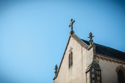 Low angle view of statue against building against clear blue sky