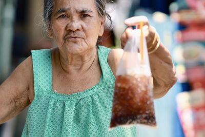 Portrait of old woman drinking glass