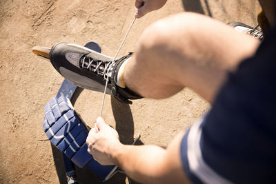 High angle view of man tying shoelace of inline skates on field