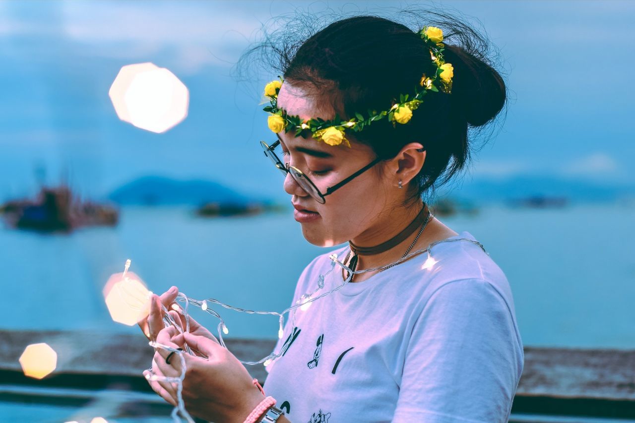 real people, one person, water, lifestyles, leisure activity, focus on foreground, sea, holding, nature, glasses, young adult, women, females, casual clothing, childhood, headshot, portrait, sunlight, outdoors