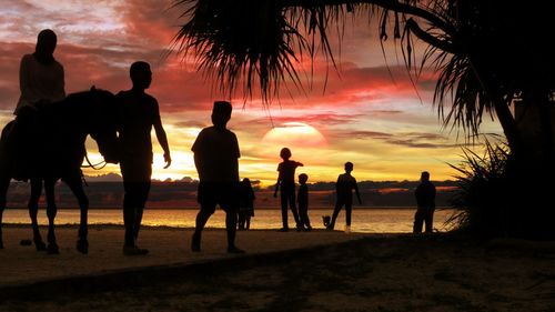 Silhouette people at beach during sunset