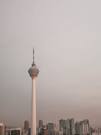 Communications tower in city against sky