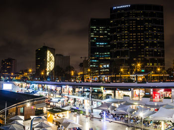 Illuminated buildings in city against sky at night