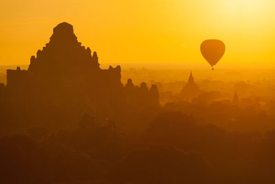 Silhouette of hot air against sky during sunset