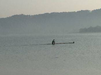 Silhouette people on sea against sky