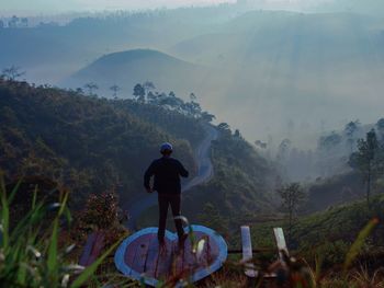 Rear view of man standing on heart shape against mountains