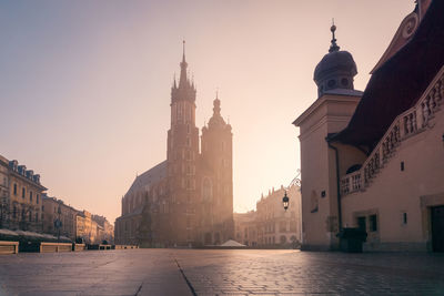 Famous empty paved main square with historic buildings with towers located in city of poland against cloudless sky in krakow