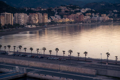 High angle view of sea against buildings in city during sunset