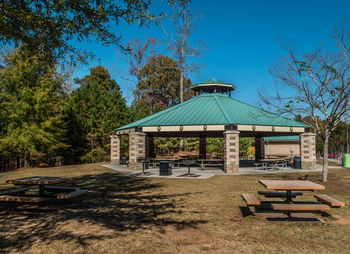 Empty bench in park against clear blue sky