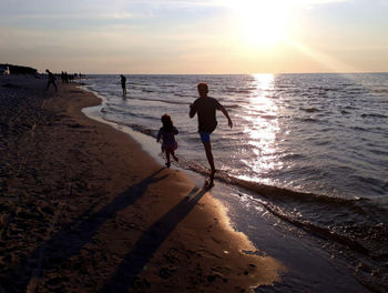 People on beach against sky during sunset