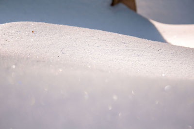 Close-up of snow on land during sunny day