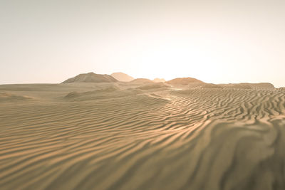 Sand dunes in desert against clear sky