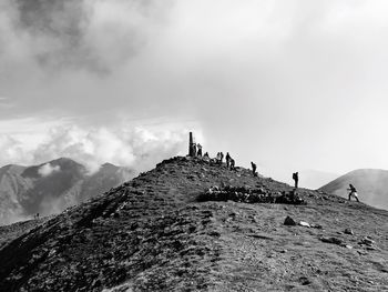 Hikers climbing on mountain against sky