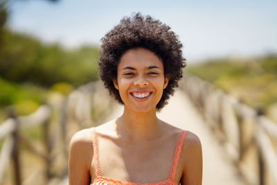 Portrait of young woman standing against fence