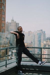 Full length of man standing by railing against buildings in city