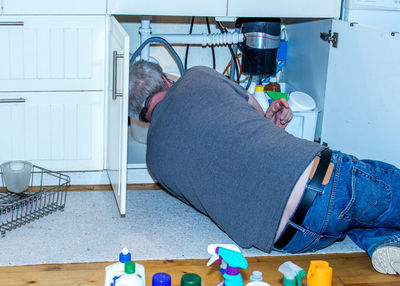 Senior man fixing a leaky pipe under the sink