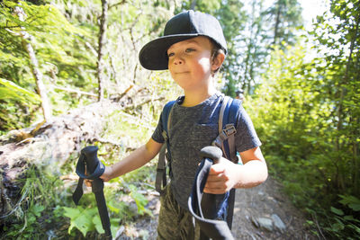 Young boy hiking with trekking poles, carrying backpack. on the move