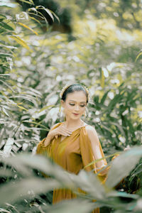 Portrait of young woman standing against plants