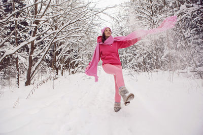 Woman run on a path in the woods in pink clothes a jacket a knitted scarf and a hat forest in winter