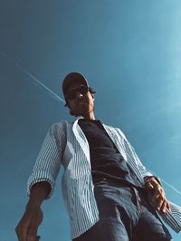 Low angle view of young man looking away against sky