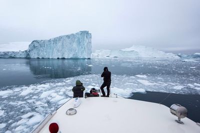 Rear view of people photographing glaciers