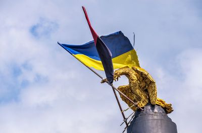 Low angle view of yellow sculpture on pole against sky