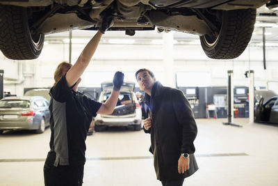 Mechanic showing car to customer in auto repair shop