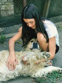 Young woman stroking dog on walkway