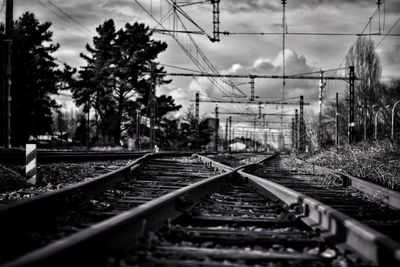 Railroad tracks and trees against cloudy sky