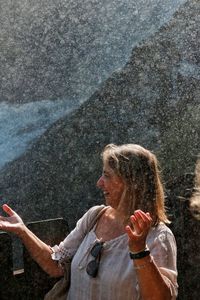 Woman with arms raised standing in water