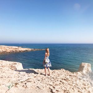 Full length of woman standing on beach against clear sky