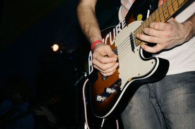 Midsection of man playing guitar