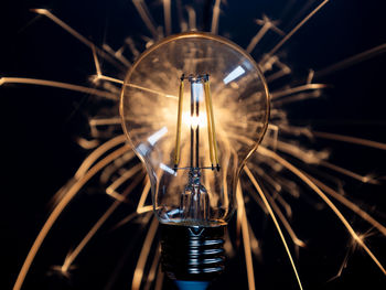 A light bulb with transparent glass in the dark with sparklers behind it