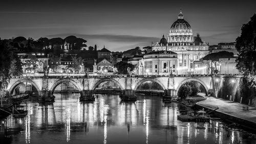 Arch bridge over river against buildings in city