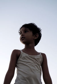 Low angle view of boy looking away against sky