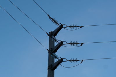 Low angle view of electricity pylon against clear sky