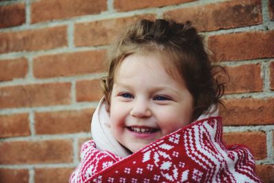 Cute smiling girl against brick wall