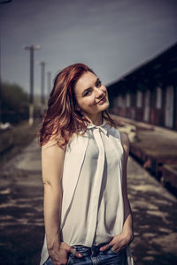 Portrait of smiling woman standing on footpath against sky