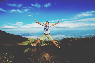 Man jumping on field against sky