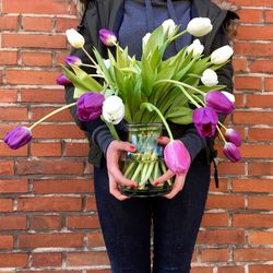 Midsection of woman holding pink flower against brick wall