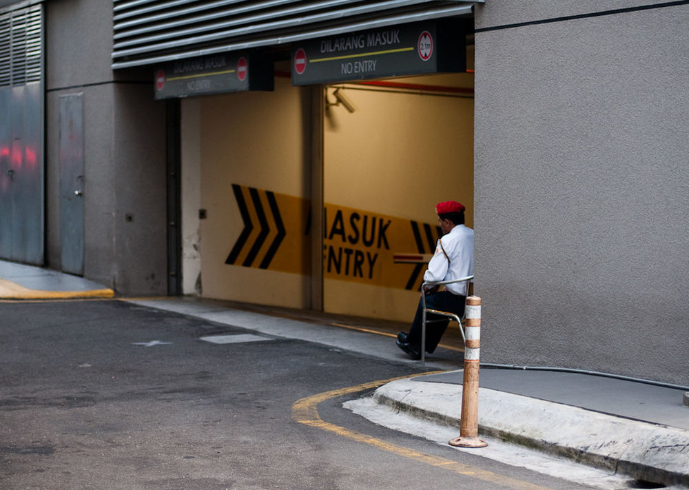 FULL LENGTH OF MAN STANDING BY ROAD SIGN