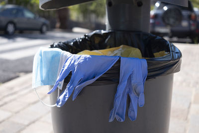 View of surgical glove and mask in dustbin outdoors
