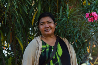 Portrait of young woman standing against plants