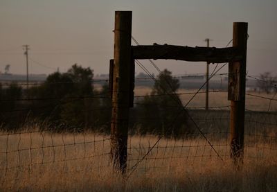 Wooden post on field against sky