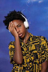 Young african american woman with short hair and modern clothes listening to music with headphones 