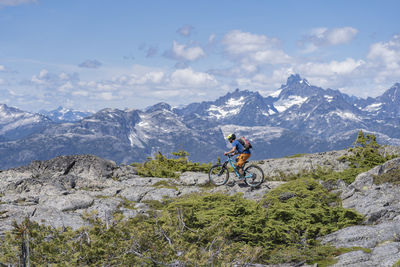 Man riding bicycle on mountain against sky