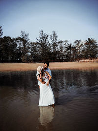 Couple romancing while standing on shore at beach