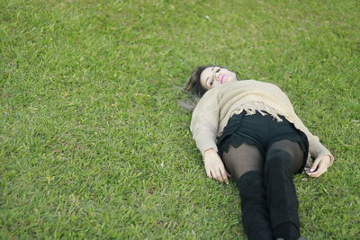 High angle portrait of young woman lying on grassy field