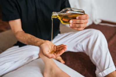 Midsection of man pouring essential oil on hand during message